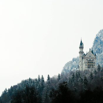 snowy castle in an evergreen landscape - get inspired to write with winter fantasy tropes