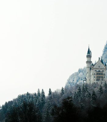 snowy castle in an evergreen landscape - get inspired to write with winter fantasy tropes